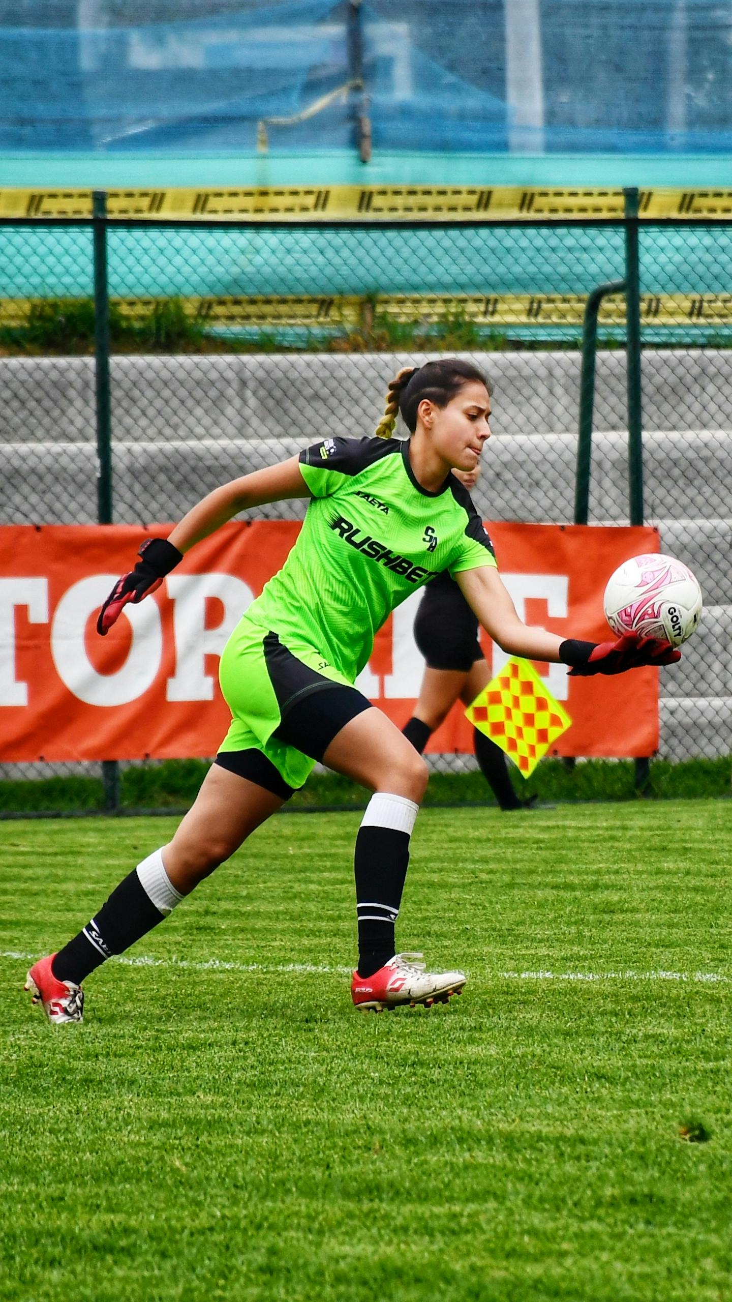 Young woman saving a goal during a soccer game on a green field.